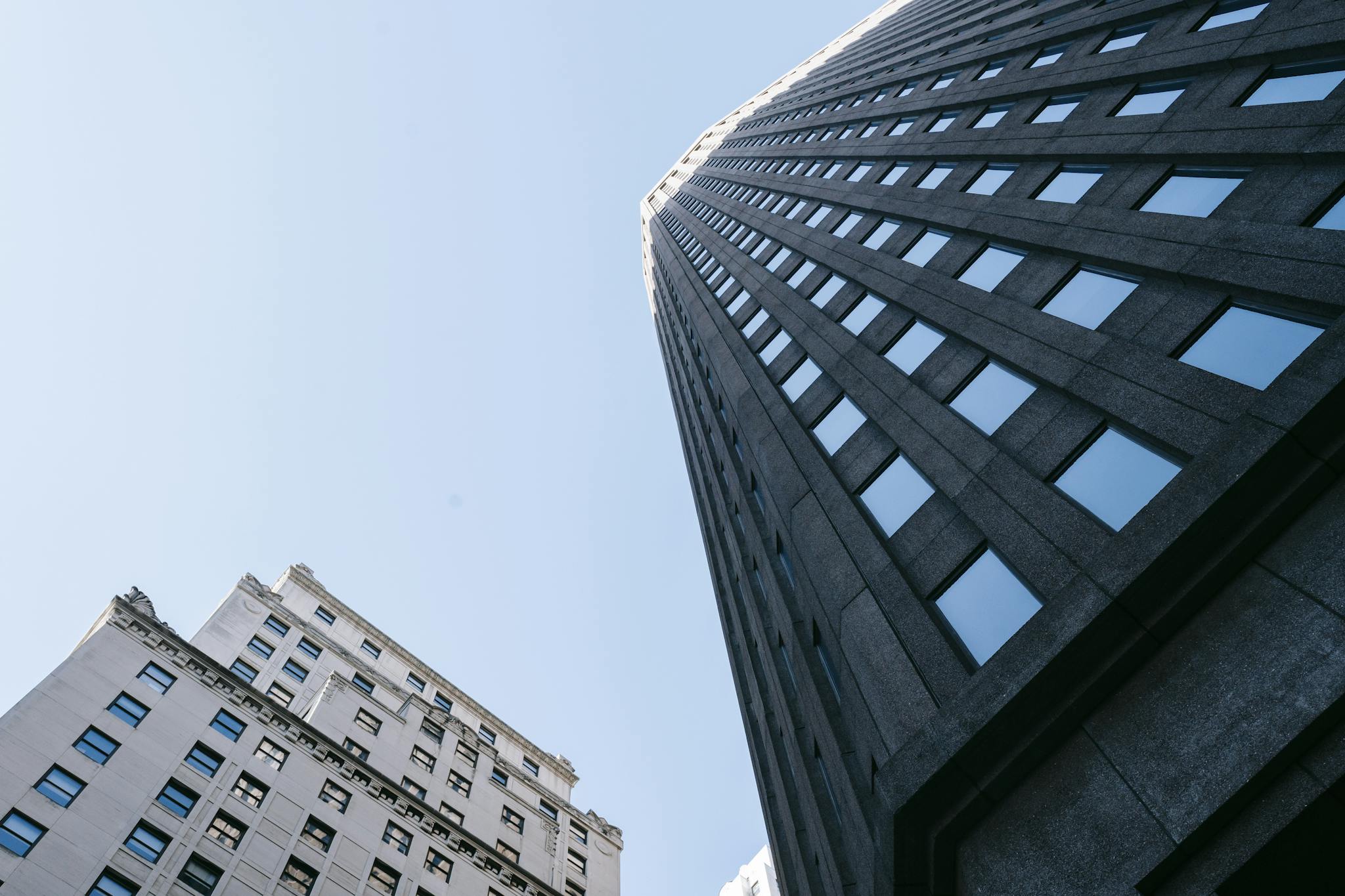 Upward view of modern skyscrapers with a clear blue sky, showcasing contemporary architecture.